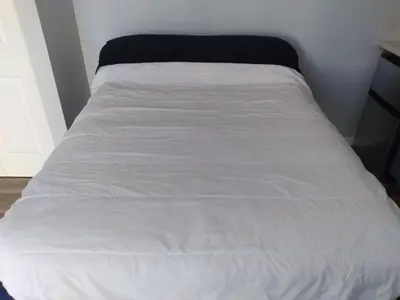 a bed with white sheets and a black blanket at Homes for Soul Los Angeles in Los Angeles