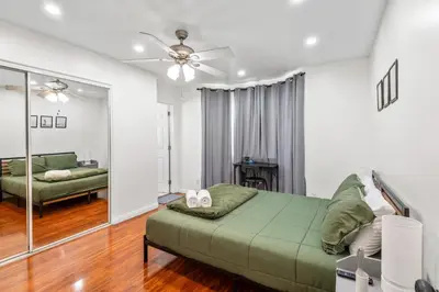 a bedroom with a green bed and a living room at Game Room & In-Unit Laundry - 15 Min to Disney! in Artesia