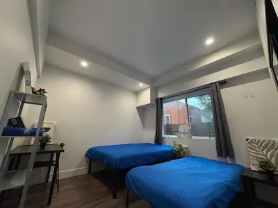 two blue beds in a room with a window at Blue Stay Walk to BMO Stadium and USC in Los Angeles