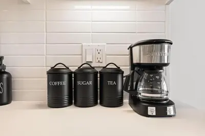 a kitchen counter with a coffeemaker and three coffee cups at Modern Living, Stunning city views, 1Mile to Dodger Stadium in Los Angeles