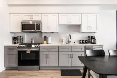 a kitchen with white cabinets and a stove and a table at The Sky loft Suite, DTLA Sunset Views in Los Angeles