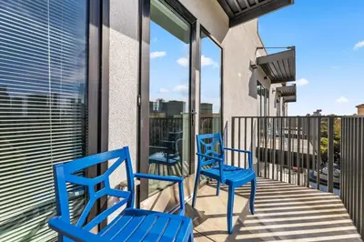two blue chairs on a balcony with windows at The Sky loft Suite, DTLA Sunset Views in Los Angeles