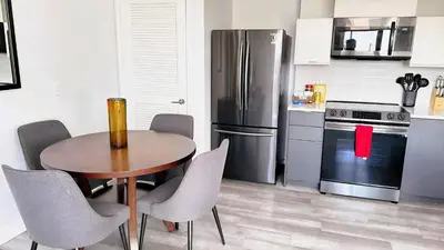 a kitchen with a table and a stainless steel refrigerator at Melrose Luxe Retreat near The Grove in Los Angeles