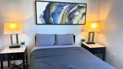 a bedroom with a bed with two lamps and a painting on the wall at Melrose Luxe Retreat near The Grove in Los Angeles