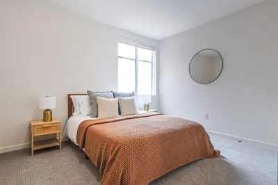 a bedroom with a bed with an orange blanket and a mirror at 2BR Condo in Santa Monica - Walking Distance to Beach, Dining, Shopping & Promenade in Los Angeles
