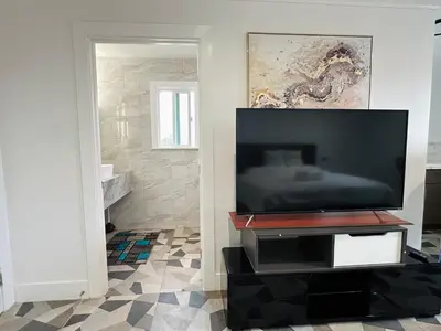 a flat screen tv sitting on a stand in a living room at Luxe Stay Room with Private Bathroom 55 in Los Angeles