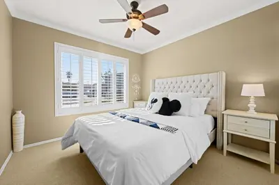 a bedroom with a white bed with a ceiling fan at The 3BR-2BA Extended Stay Oasis in Anaheim in Anaheim
