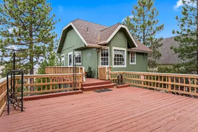 a green house with a wooden deck at Casa de Yukon & Black stone Grill, 3 Level Home in Lake Arrowhead