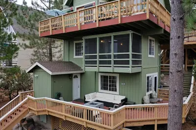 a green house with a balcony and a tree at Casa de Yukon & Black stone Grill, 3 Level Home in Lake Arrowhead