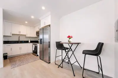 a kitchen with a table and two chairs and a refrigerator at Prestige Studio Haven at Burbank in Burbank