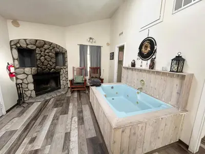 a large tub in a room with a stone fireplace at Pine Knot Guest Ranch in Big Bear Lake