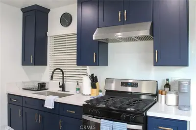 a kitchen with blue cabinets and a stove and a sink at Single family house in Long Beach