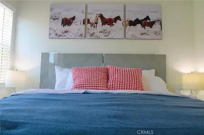a bedroom with a blue bed with two paintings of horses at Single family house in Long Beach