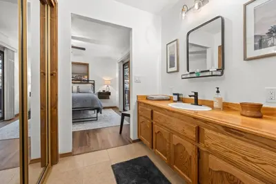 a bathroom with a sink and a mirror and a bed at Nest and Needles in Big Bear Lake