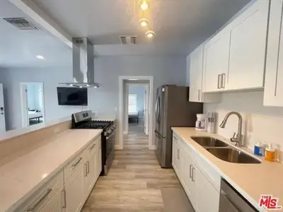 a kitchen with white cabinets and a sink and a refrigerator at Los Angeles Cozy Vibe in Los Angeles