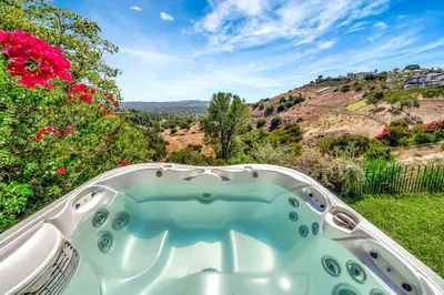 a hot tub in a yard with flowers at Stunning Hilltop 5BR With View And Hot Tub! in Lakeside Park