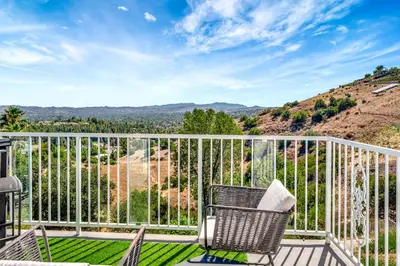 a balcony with a chair and a view of the mountains at Stunning Hilltop 5BR With View And Hot Tub! in Lakeside Park