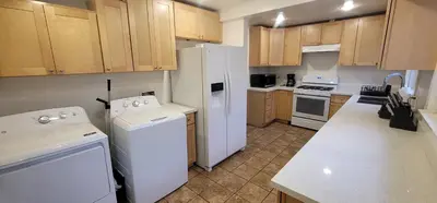 a kitchen with white appliances and wooden cabinets at Private 3 bedroom Home in Los Angeles - Gardena, California in Gardena