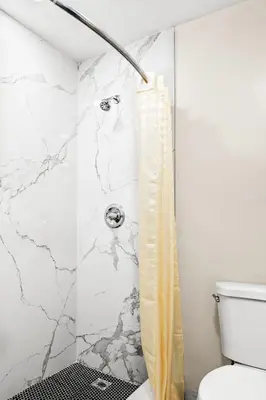 a bathroom with a shower with a marble wall at La Mirage Inn - Long Beach in Long Beach