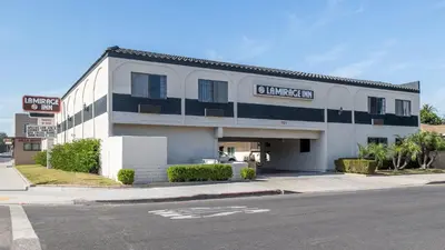 a white building with a sign on the side of it at La Mirage Inn - Long Beach in Long Beach