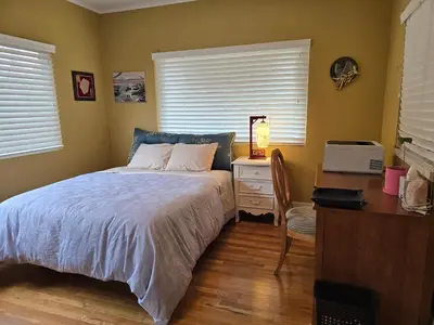 a bedroom with a bed and a desk and windows at The Ginkgo House in Pasadena