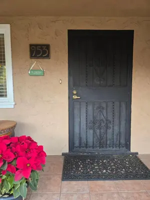 a black door on the side of a house with red flowers at The Ginkgo House in Pasadena