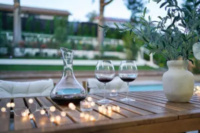 two glasses of wine on a wooden table with lights at Luxe Sundance Villa 3BR with Pool and Spa Near Disney in Pomona