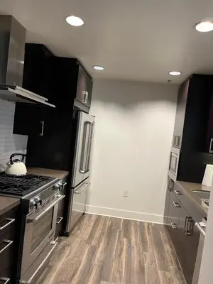 a kitchen with stainless steel appliances and wooden floors at HollywoodNorth in Los Angeles