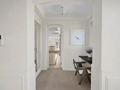 a white hallway with a table and a clock on the wall at Savona Sanctuary Estate in Los Angeles