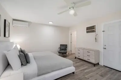 a white bedroom with a bed and a chair at Newly Renovated Home Spacious Close 2 Hospital in San Bernardino