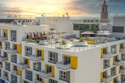 a building with balconies and a sunset in the background at Modern Hollywood Walk of Fame Apts- Free Parking, 360 Rooftop, Pool, Gym- Centrally located in Los Angeles