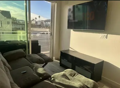 a living room with a couch and a large window at Modern Hollywood Walk of Fame Apts- Free Parking, 360 Rooftop, Pool, Gym- Centrally located in Los Angeles