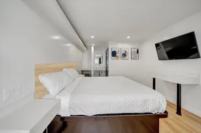 a white bedroom with a bed and a flat screen tv at Casablanca Inn in Bell