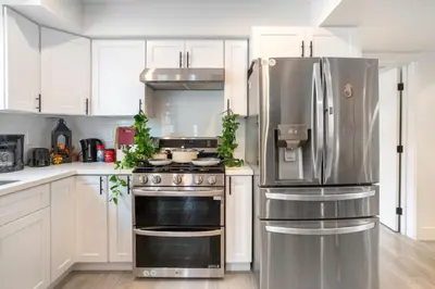 a kitchen with white cabinets and a stainless steel refrigerator at Cozy Urban Retreat near Downtown LA & USC - Private room with shared Living room and kitchen in Los Angeles