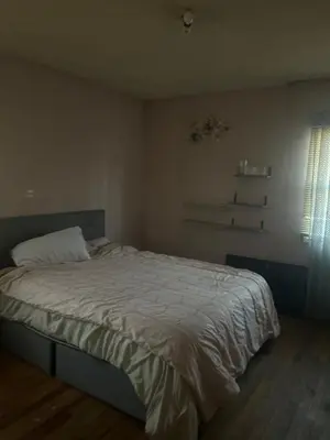 a bedroom with a bed with a white comforter and a window at Cheryls home in Inglewood