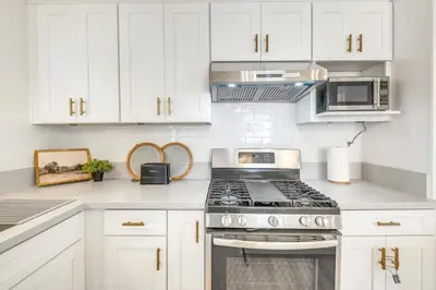 a white kitchen with a stove and a microwave at Centrally Located Charming LA Home with Food Scenes in Monterey Park