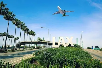 an airplane flying over a freeway with a large lax sign at Cozy Spacious, free parking, near it all in South Gate