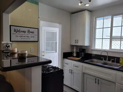 a kitchen with white cabinets and a black counter top at Cozy Spacious, free parking, near it all in South Gate