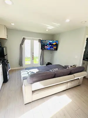 a large bed in a room with a television on the wall at Cozy Serene Studio Backhouse w parking near it all in South Gate
