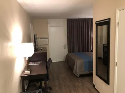 a hotel room with a bed and a desk and a mirror at Inn Of Long Beach in Long Beach