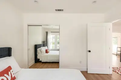 a white bedroom with a bed and a mirror at Stylish Gated Retreat in East Hollywood with Parking in Los Angeles