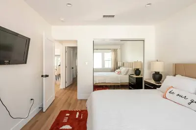 a white bedroom with a bed and a large mirror at Stylish Gated Retreat in East Hollywood with Parking in Los Angeles