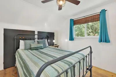 a bedroom with a bed with blue curtains and a window at Village Relaxation at Camp Conklin Big Bear - Hot Tub in Big Bear Lake