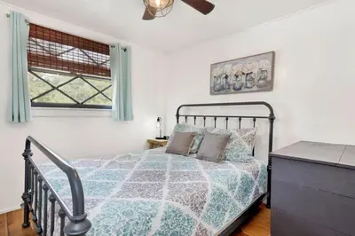 a bedroom with a bed and a dresser and two windows at Village Relaxation at Camp Conklin Big Bear - Hot Tub in Big Bear Lake