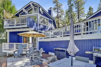 a blue house with a table and an umbrella at Serenity Cove Lake House by Big Bear Vacations in Big Bear Lake