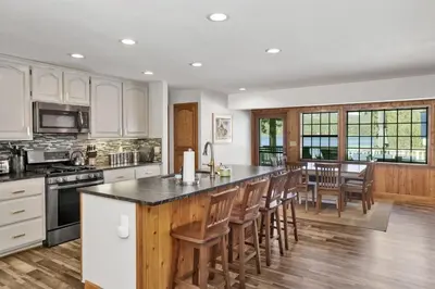 a kitchen with white cabinets and a large island with chairs at Serenity Cove Lake House by Big Bear Vacations in Big Bear Lake