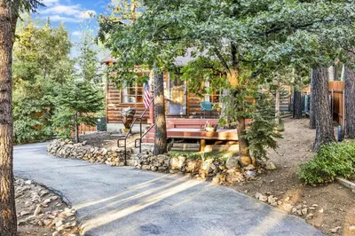 a log cabin with a bench and an american flag at The Nest on Towne Trail by Big Bear Vacations in Big Bear Lake