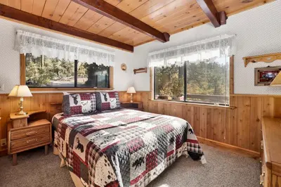 a bedroom with a bed and two windows at Mountain Hideaway on Maryland by Big Bear Vacations in Big Bear Lake