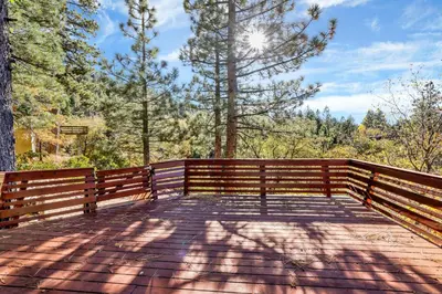 a wooden bridge with the sun shining through the trees at Mountain Hideaway on Maryland by Big Bear Vacations in Big Bear Lake