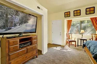 a bedroom with a large flat screen tv on a wooden dresser at Buttercup Snow Summit Condo by Big Bear Vacations in Big Bear Lake